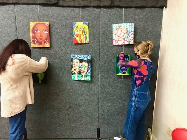 Students hang their works of art at the Rogers Experimental House